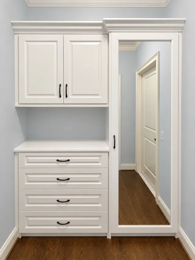 White raised-panel wardrobe with upper cabinets, an open niche over a four-drawer dresser and a full-length mirrored door