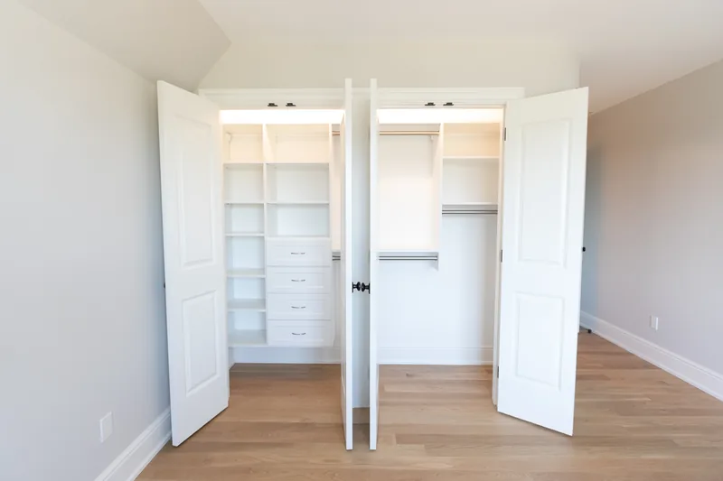 Two white reach-in closets with lit shelving, drawers and hanging