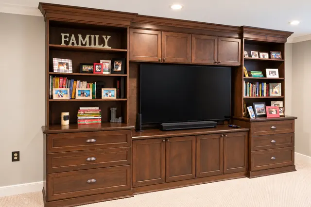 Cherry-finish entertainment center with a TV, open bookshelves, upper cabinets and drawer stacks