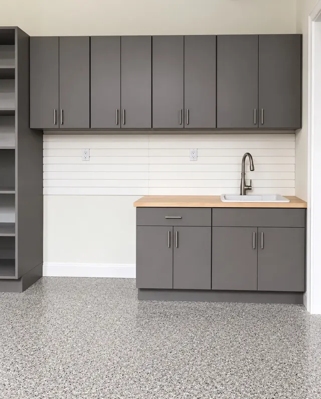 Gray garage cabinets with a butcher block counter, utility sink and white slatwall backsplash beside open shelving
