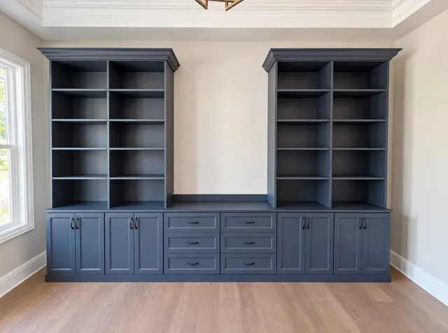 Navy twin bookcases with crown molding over a long base of cabinets and drawers