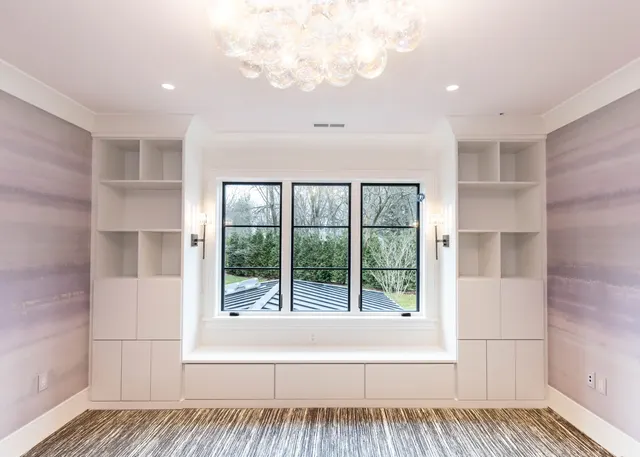 White window bench with drawers between bookcases with open cubbies and cabinets, under a bubble chandelier