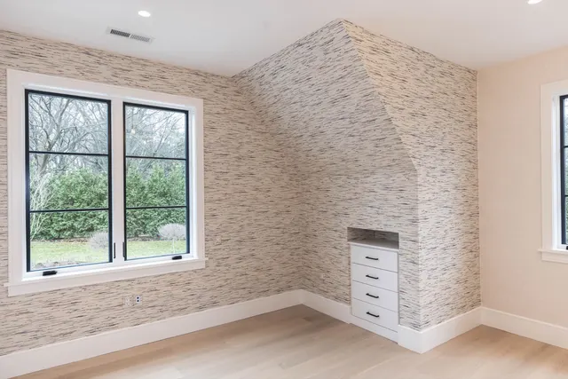 White drawer stack with a small open niche built into a sloped papered wall