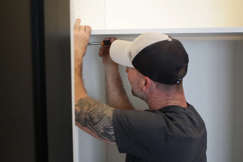 Diplomat installer leveling a custom closet panel during installation