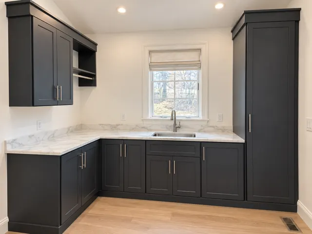 Charcoal shaker laundry cabinets with a marble-look counter, sink, tall cabinet and hanging rod under a window