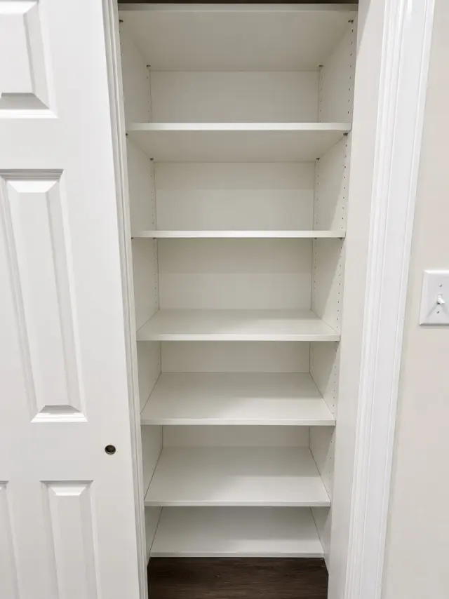 Linen closet with white adjustable shelving behind a single paneled door