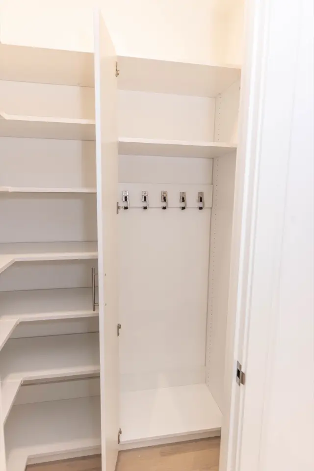Linen closet with corner shelving and a hook panel on the door side