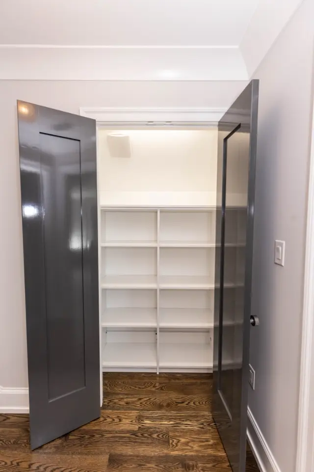 Charcoal double doors open to lit white linen shelving
