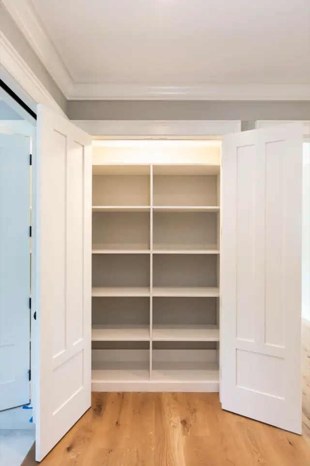 Double-door linen closet with tall white shelving