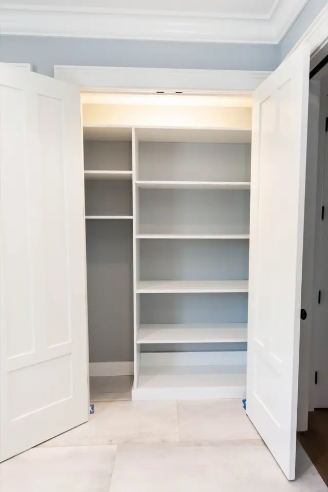 Double-door linen closet with lit shelving and a tall open section