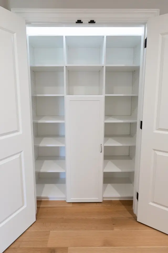 Double-door linen closet with white shelving and a center cabinet