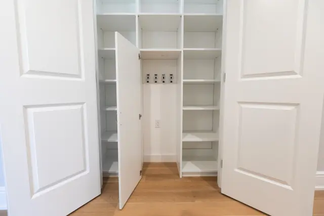 Linen closet with shelving on both sides of a center door with hooks