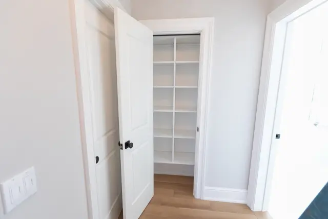 Hallway linen closet with a single door open to white shelving
