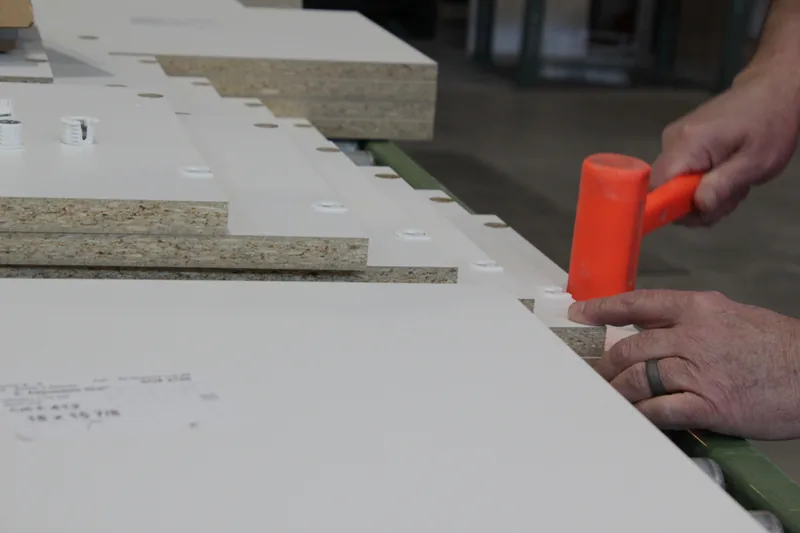 Diplomat craftsman edge banding a cabinet panel in the Downingtown shop