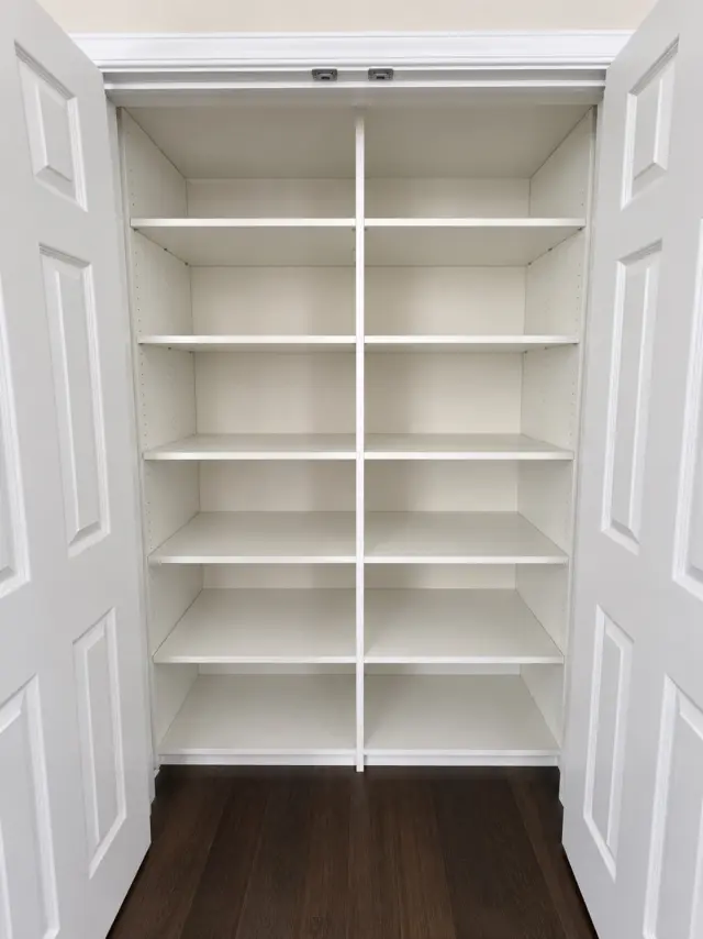 Reach-in closet with double doors open to full-height white adjustable shelving