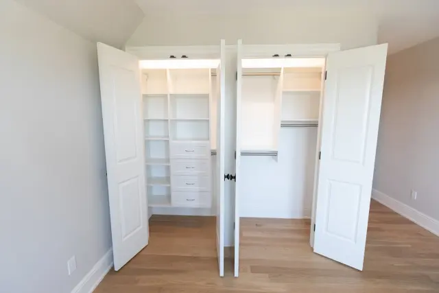 Two open closets side by side with lit shelving and hanging