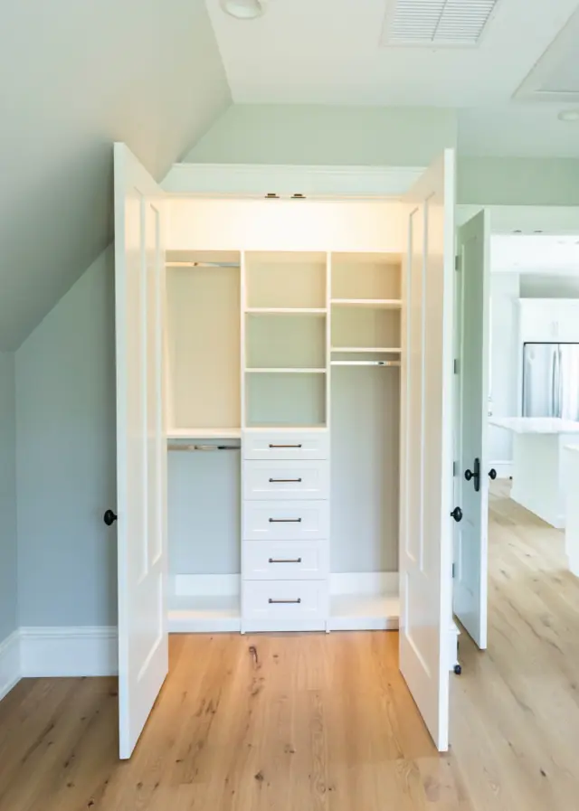 Double-door closet with lit shelves, hanging and a drawer stack