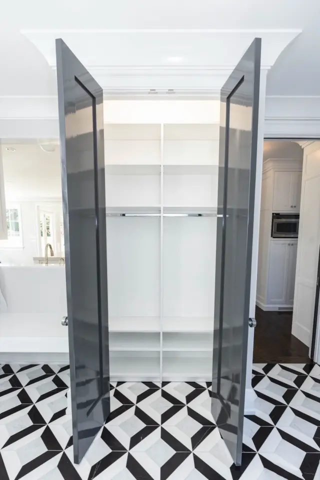 Charcoal doors open to lit white shelving above a black-and-white patterned tile floor