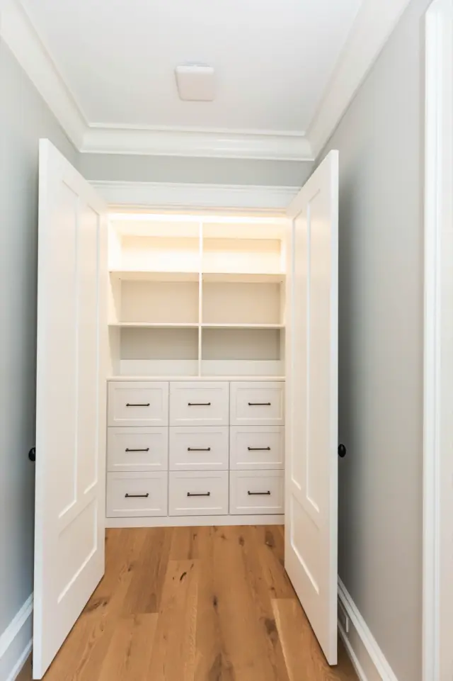 Double-door closet with lit shelves above a bank of white drawers
