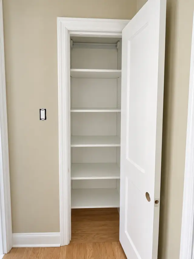 Narrow closet with adjustable white shelving behind a single door