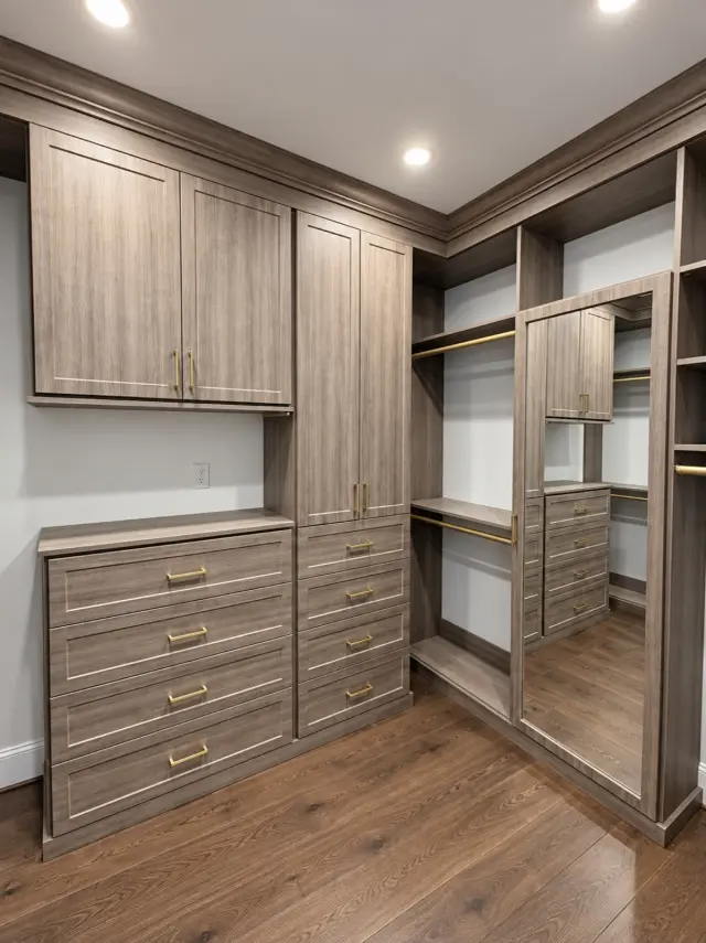 Walk-in closet in gray wood-grain with upper cabinets, a drawer bank and a full-length mirror