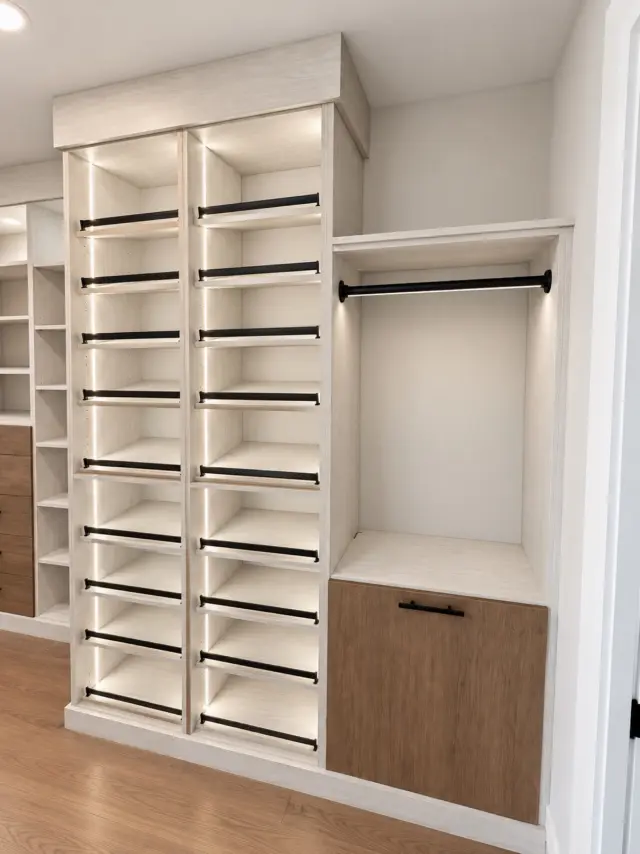 White shoe shelving tower beside lit hanging and a wood-front hamper