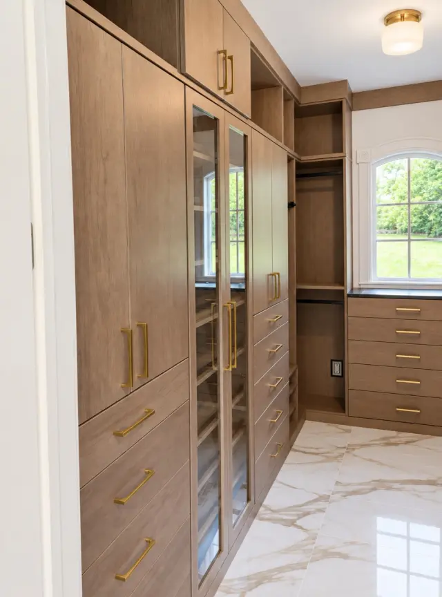 Oak walk-in closet with glass doors, brass handles and a marble floor