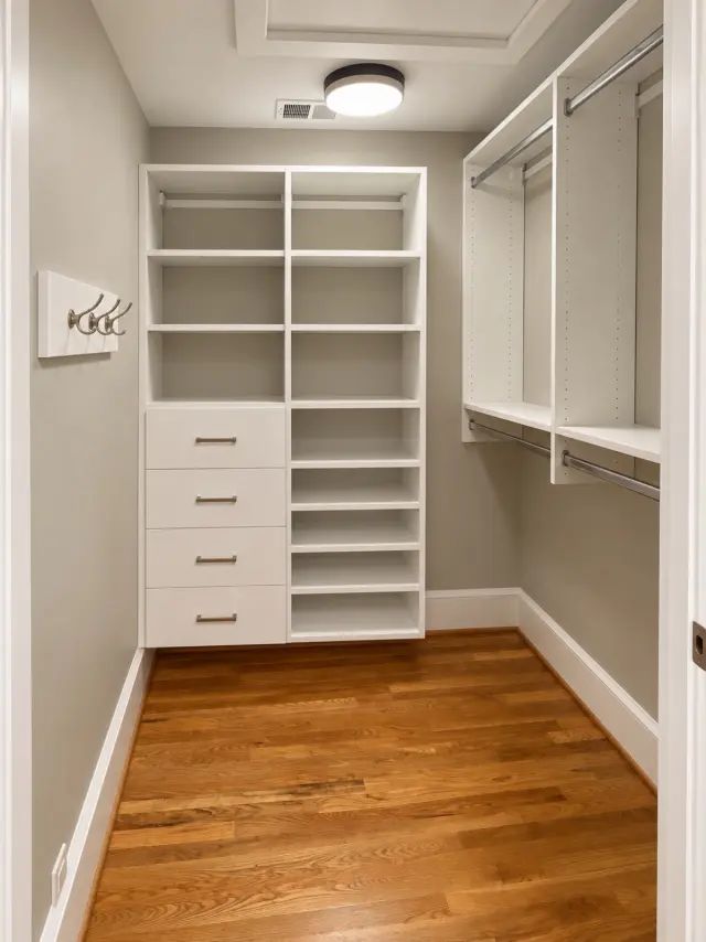 White closet with drawers, shelving and hooks on a gray wall