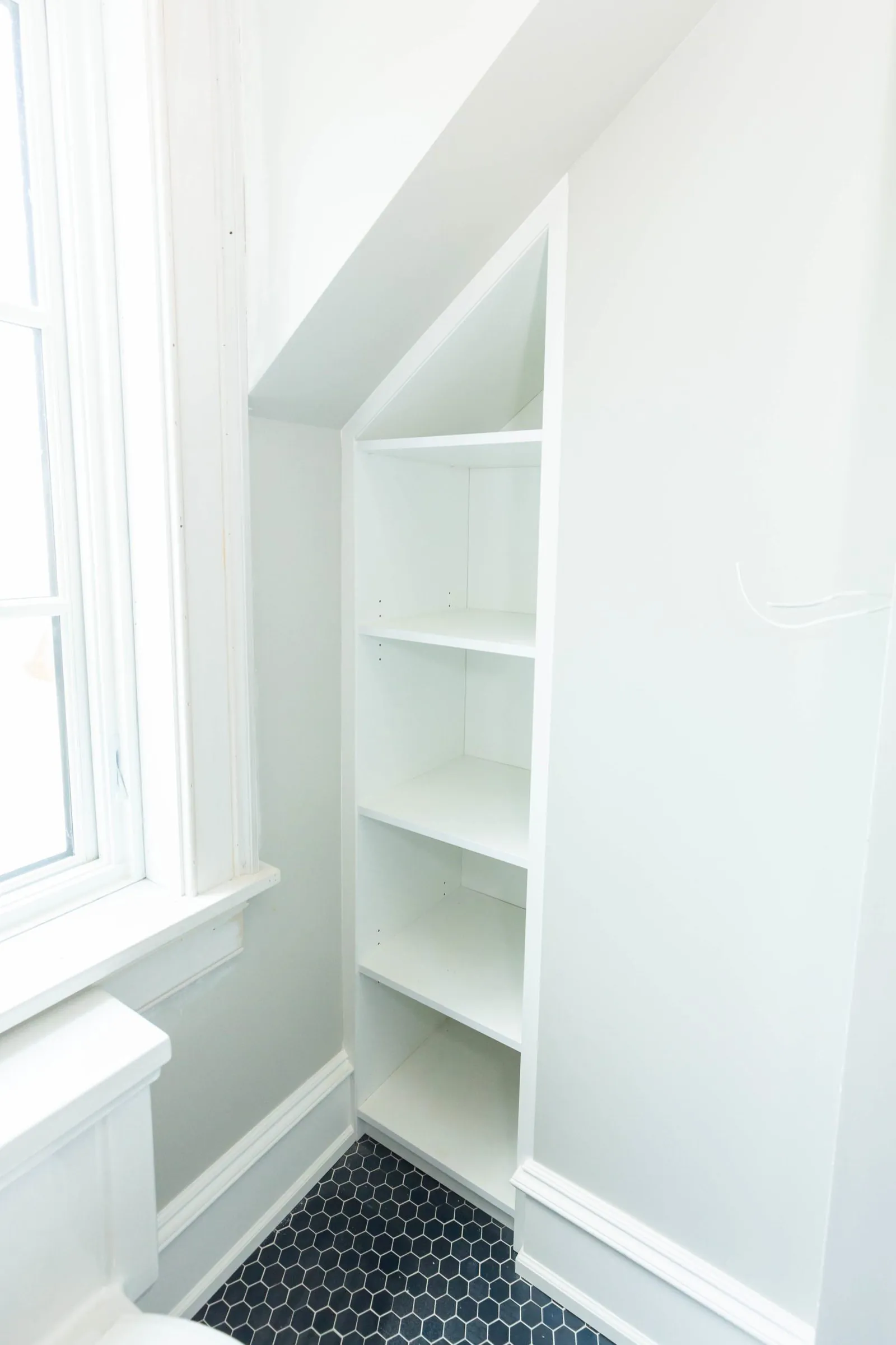 White built-in shelving set into a wall niche under a sloped ceiling