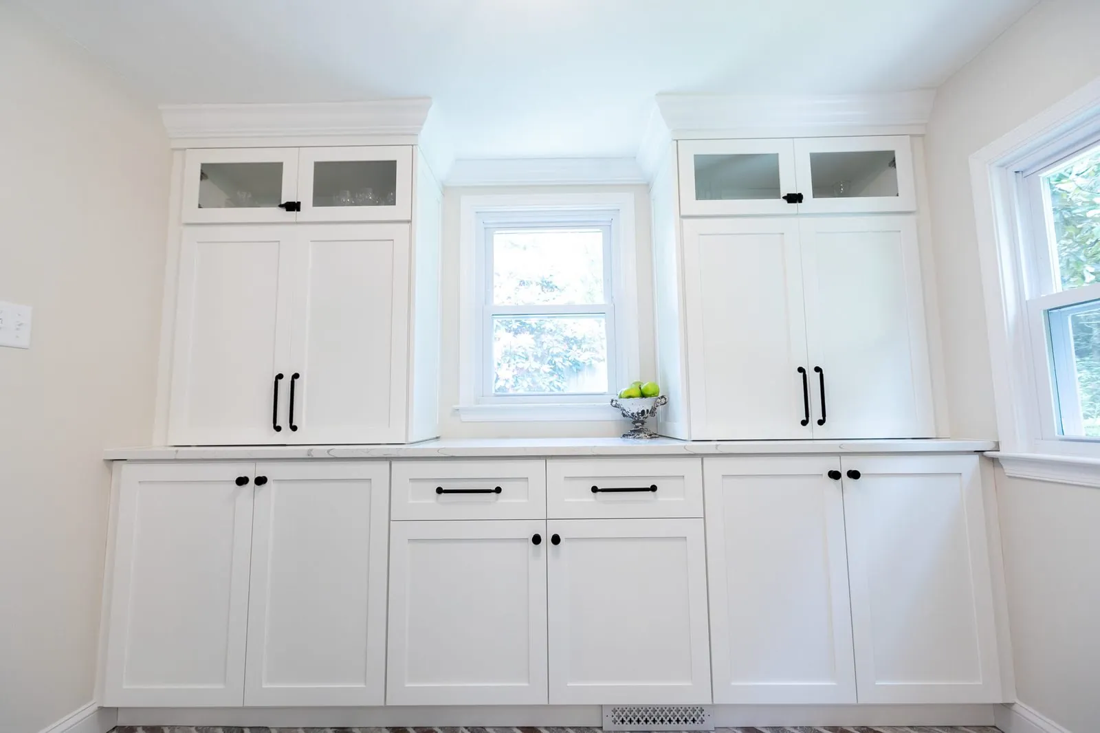 White built-in cabinets with glass-front uppers around a window