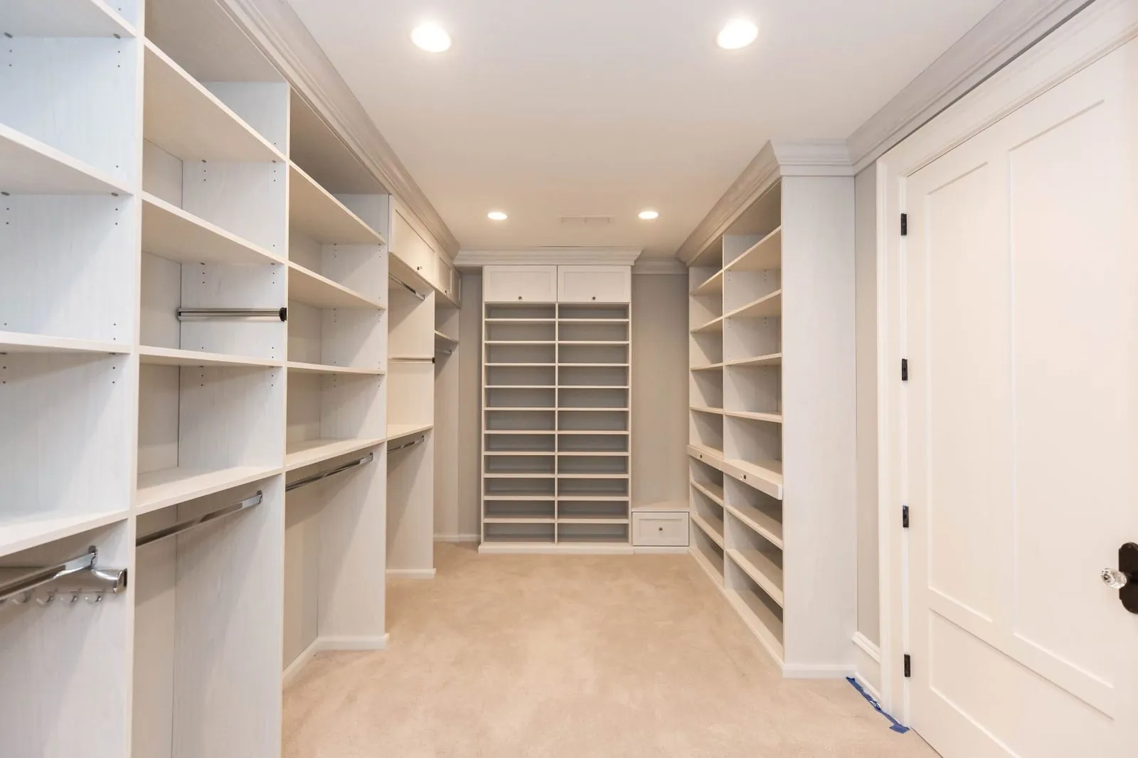 White walk-in closet with tall shelving and hanging on both sides