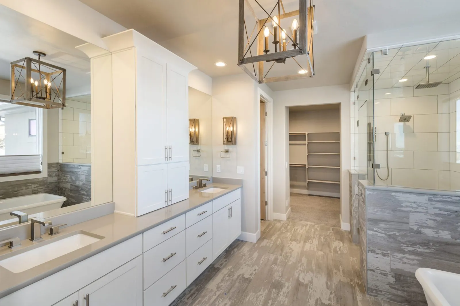 White bathroom vanity with tall cabinets beside a glass shower