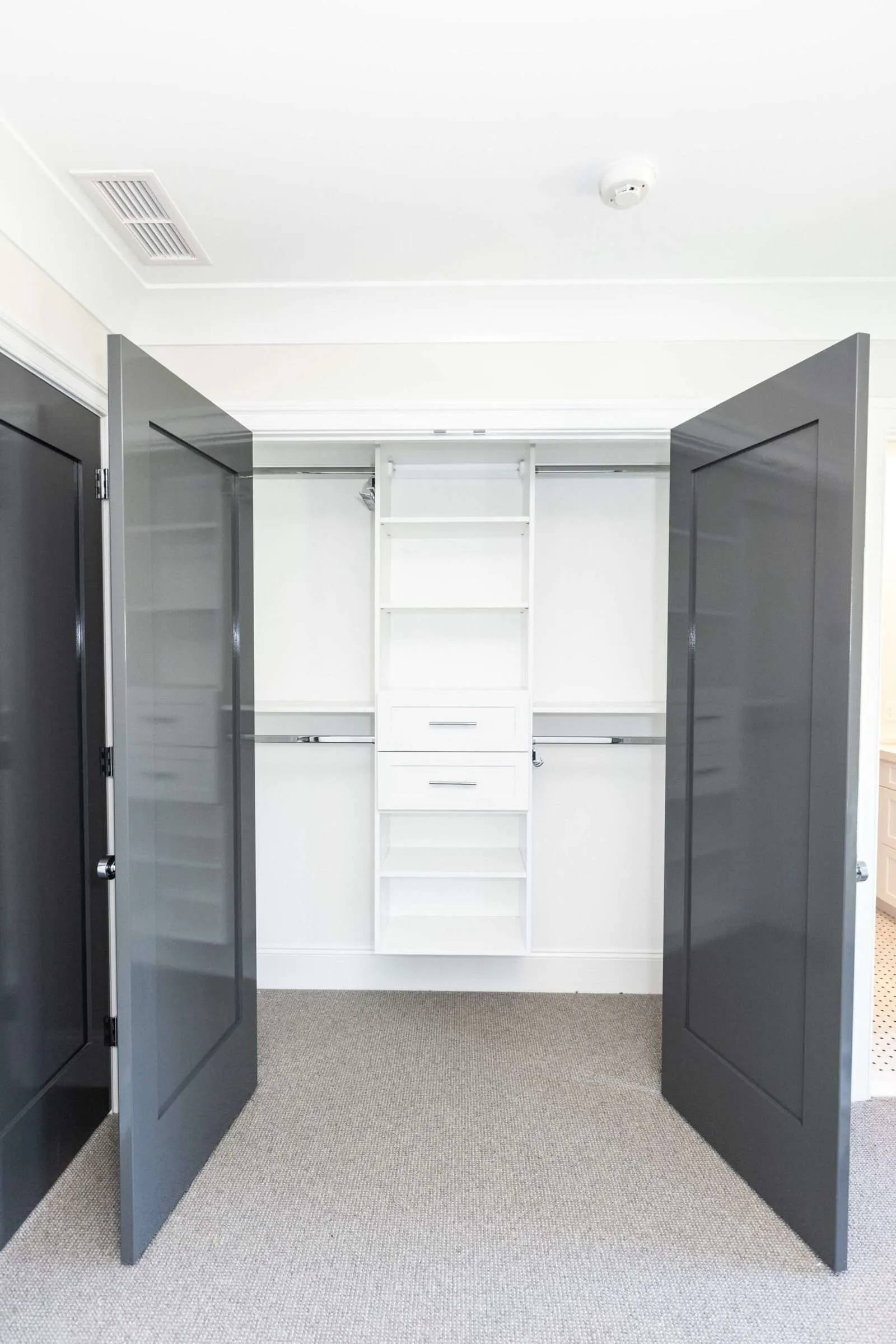Charcoal double doors open to a white reach-in closet with hanging and drawers