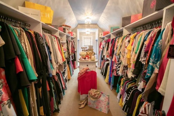 Long walk-in closet packed with colorful hanging clothes