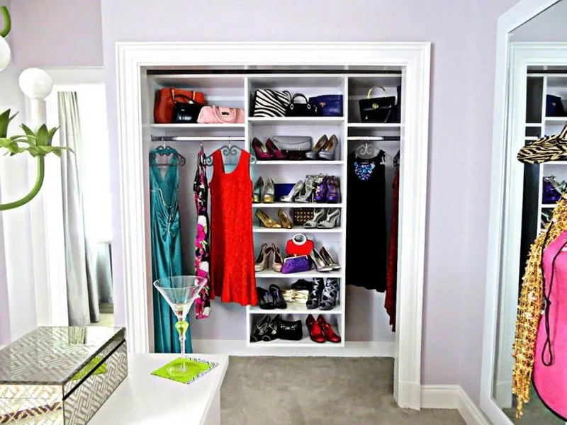 Reach-in closet with shoe shelving and hanging clothes beside a mirror