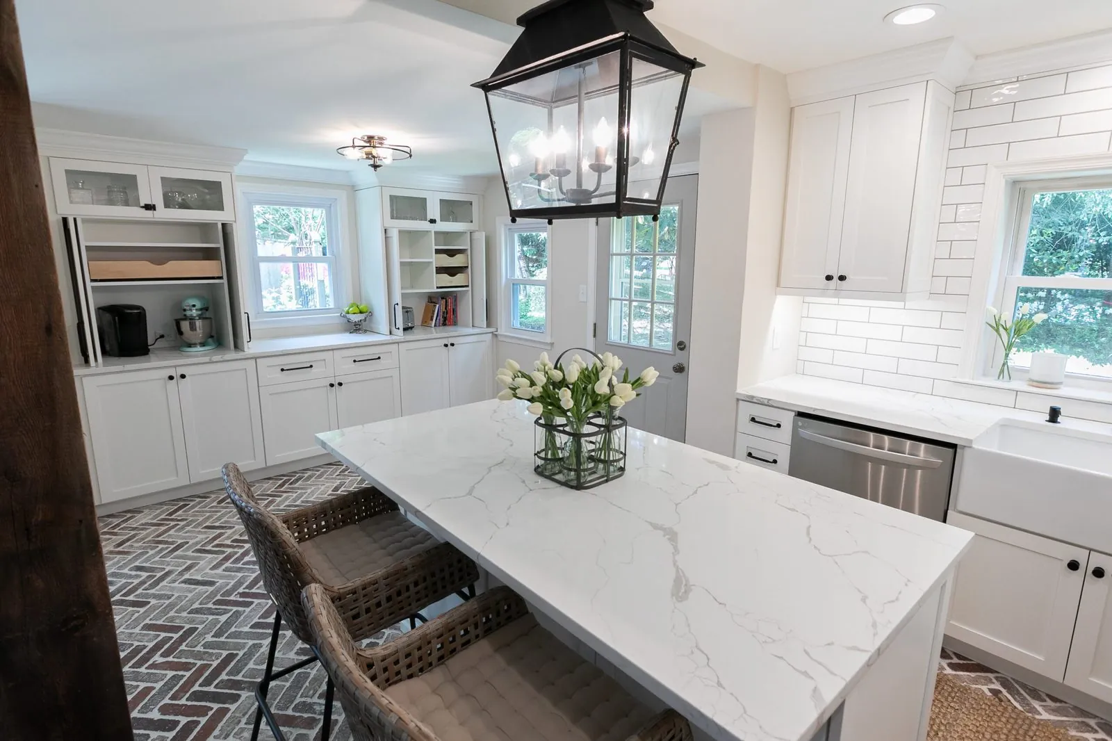 White kitchen with a marble island under a lantern pendant