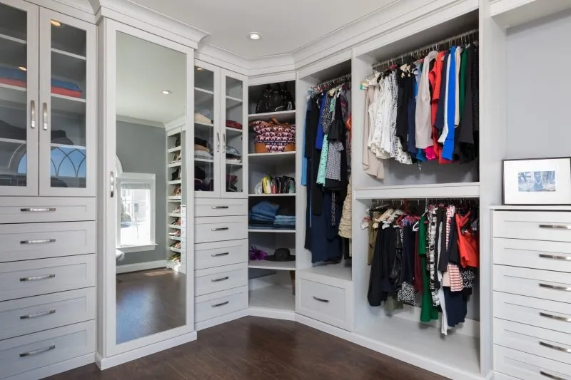 White walk-in closet with glass-door cabinets, a mirror, hanging and drawers