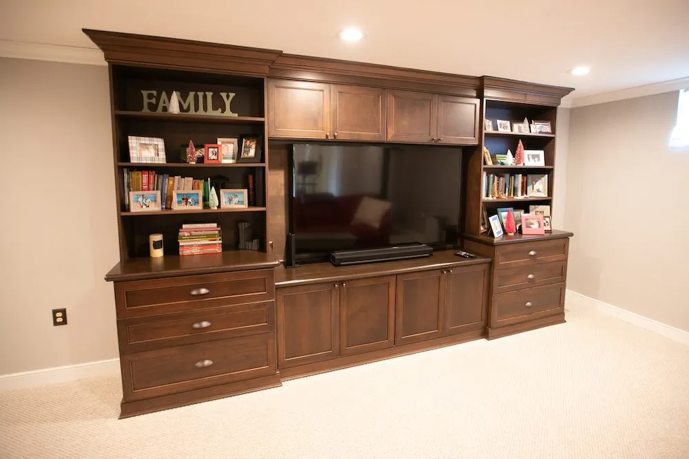 Dark wood entertainment center with a TV, open shelves and drawers