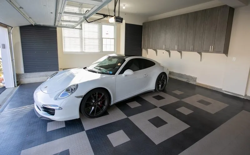 Garage with gray wall cabinets beside a white sports car on a patterned floor