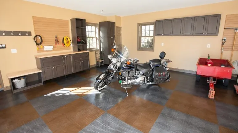 Garage with gray cabinets, a pegboard wall and a motorcycle on a checkered floor