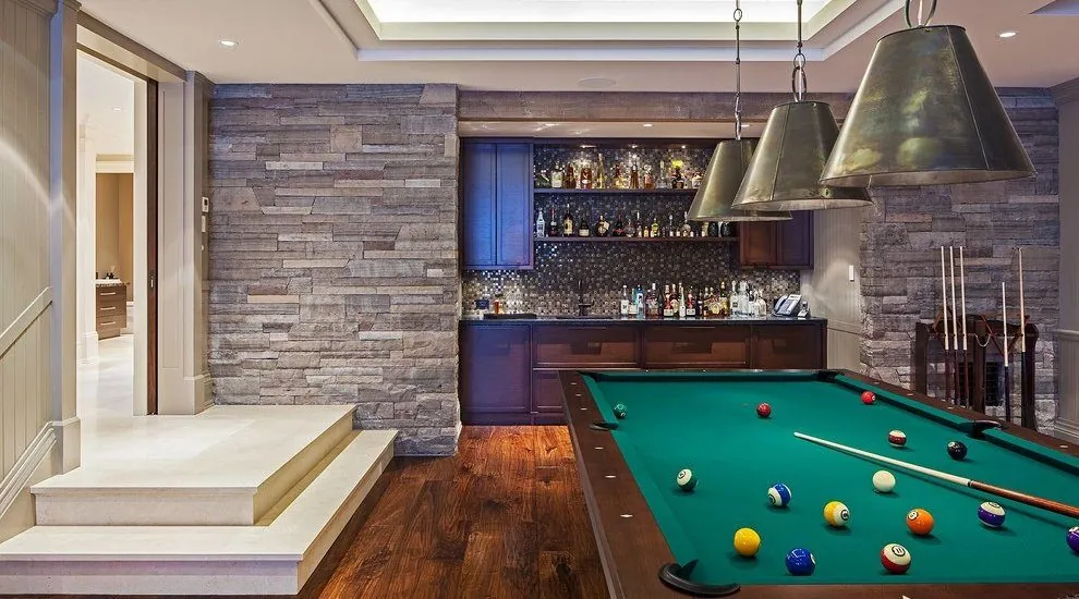 Basement with a stone accent wall, a bar and a pool table