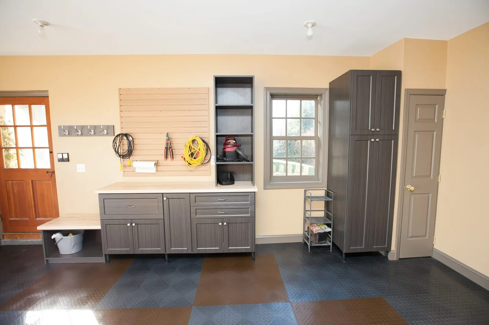 Garage with gray cabinets, a pegboard wall and a hanging bike