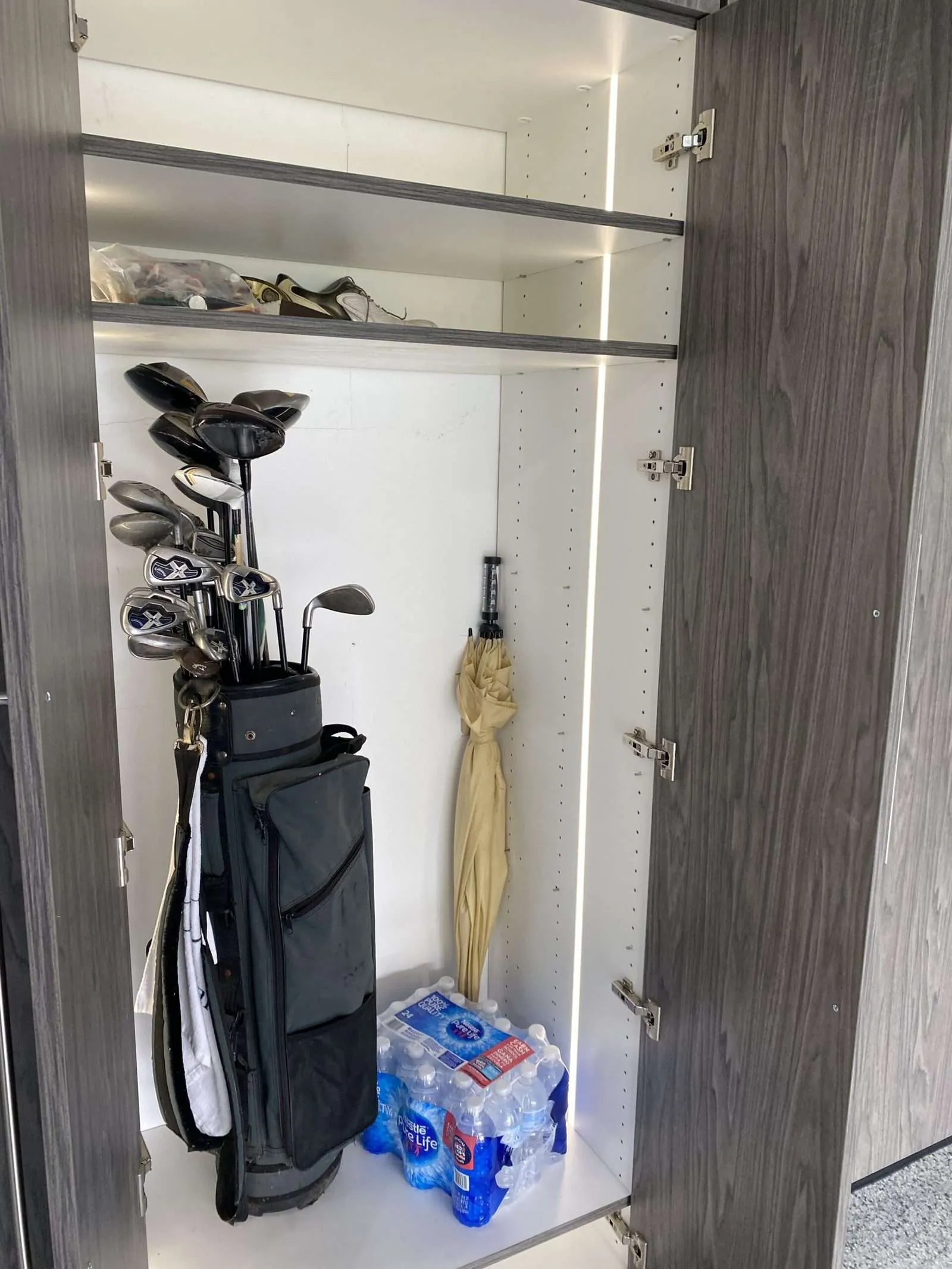 Closet with golf clubs and sports gear on hooks and shelves