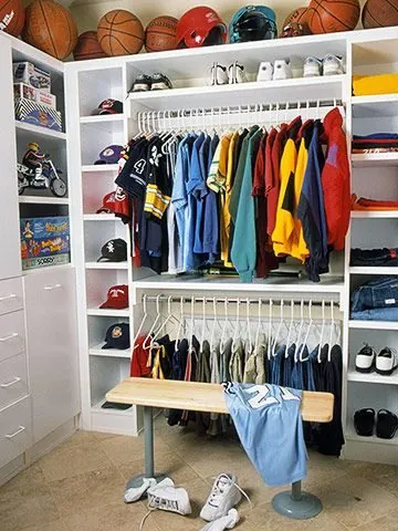Children's closet with sports balls on a top shelf, hanging clothes and shoes on the floor