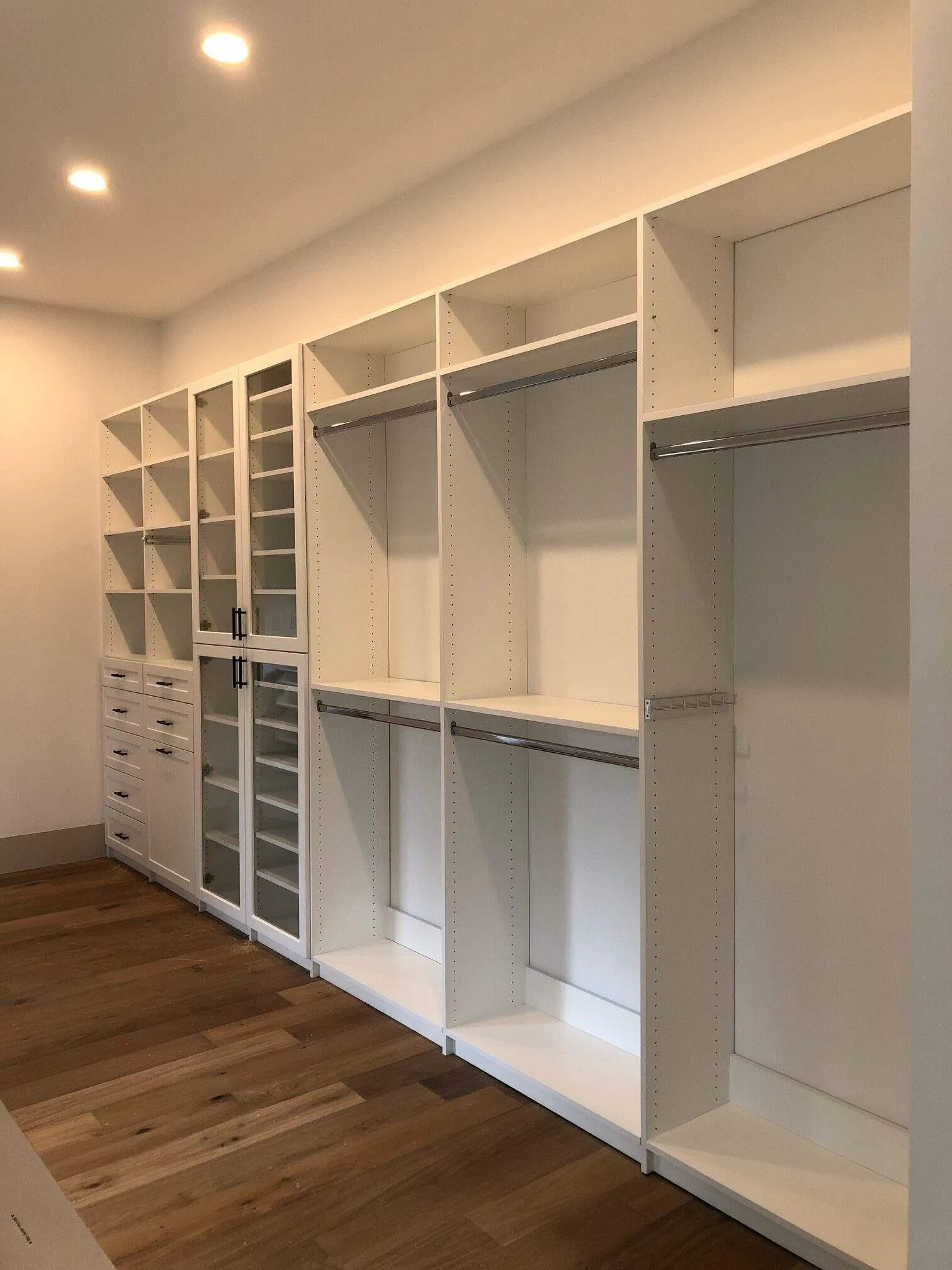 White walk-in closet with open shelving and hanging on several walls