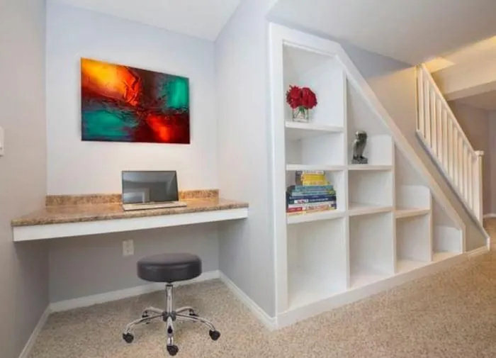 White desk and shelving built under a staircase
