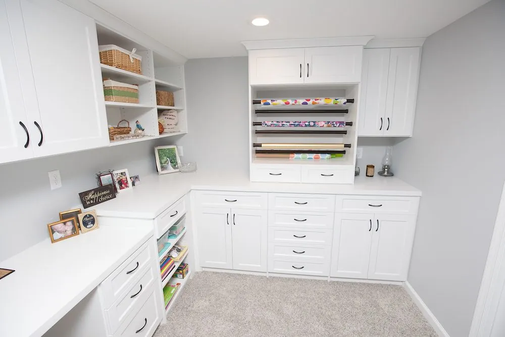 White home office with a long desk, upper cabinets, cubbies and drawers