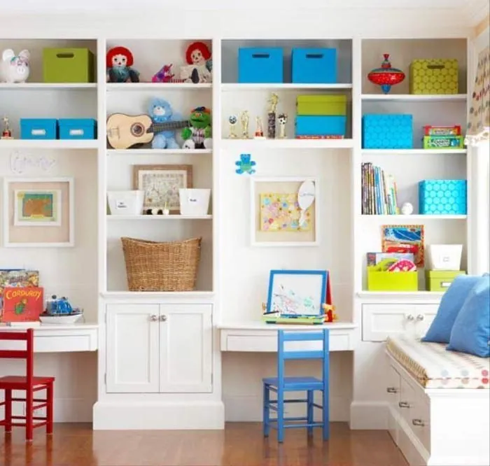 White built-in desks with cubbies, colorful bins and shelving