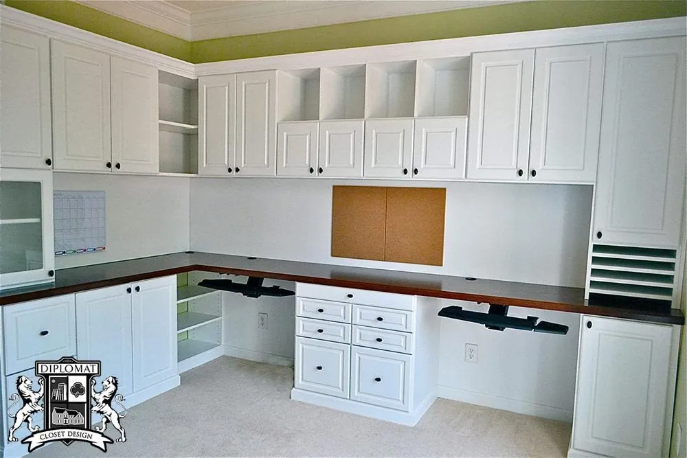 White home office with a long L-shaped desk, upper cabinets and cubbies