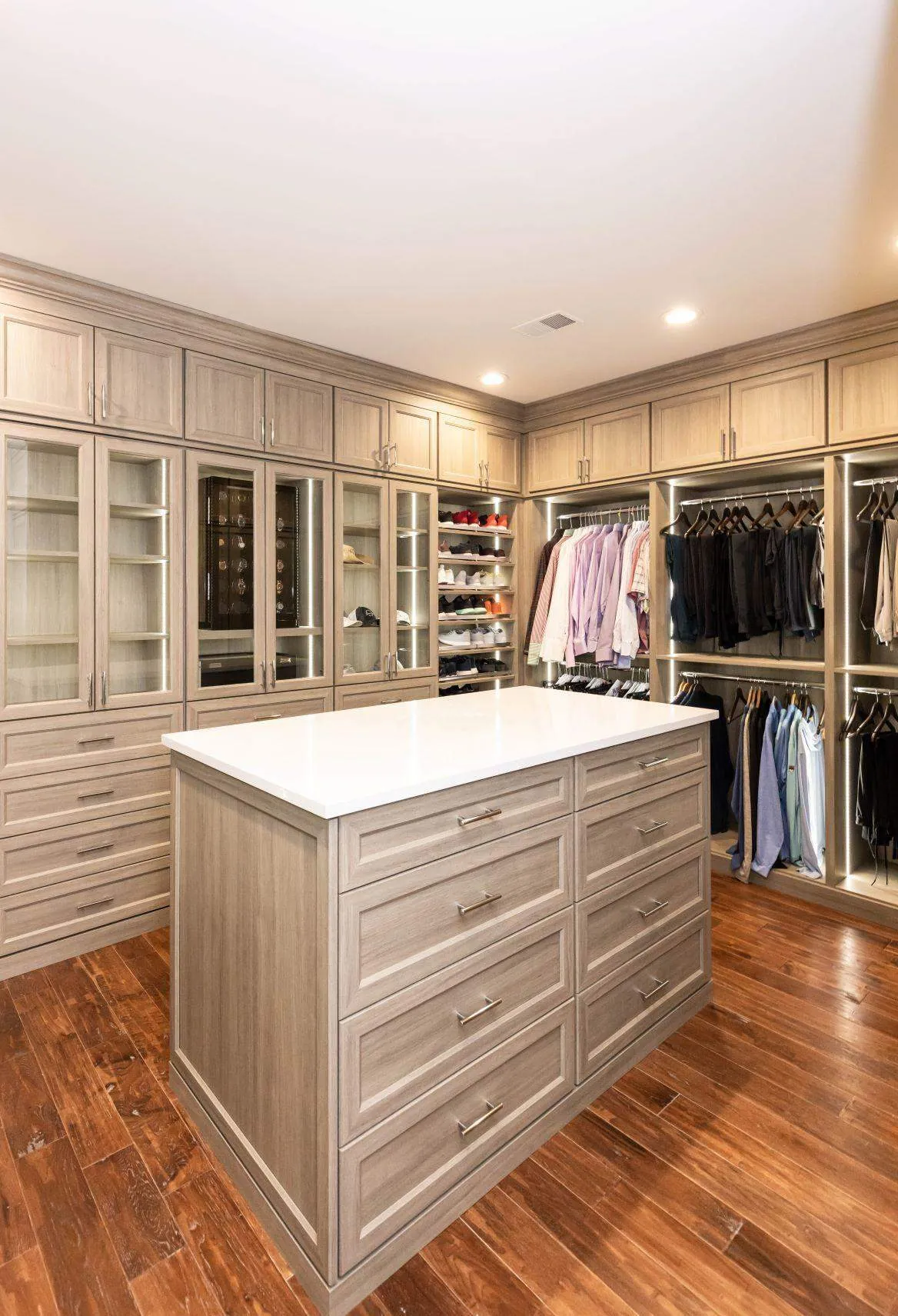 Walk-in closet with a wood-grain island, cabinets and hanging